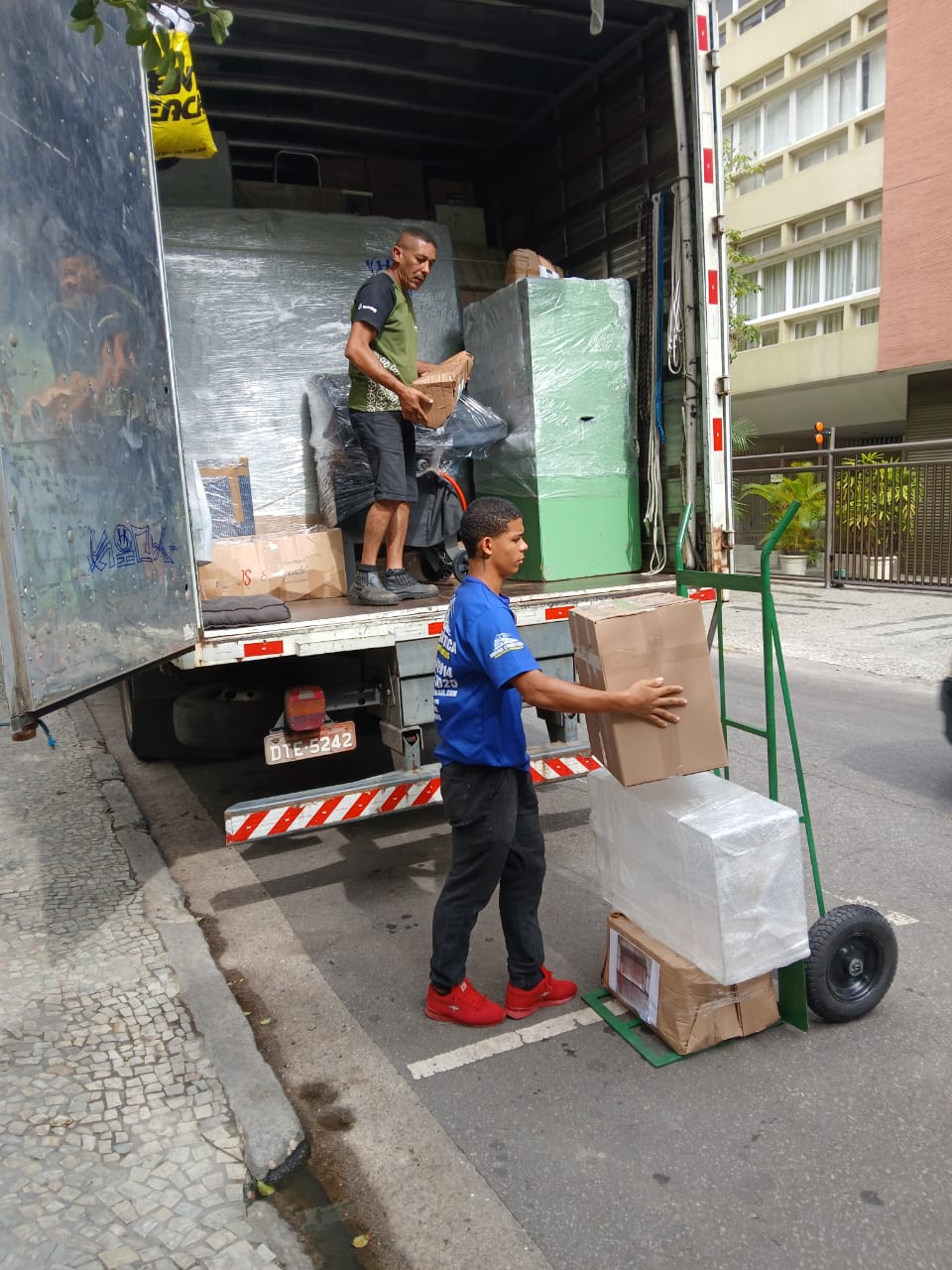 Profissional descendo caixas do caminhão com carrinho de carga