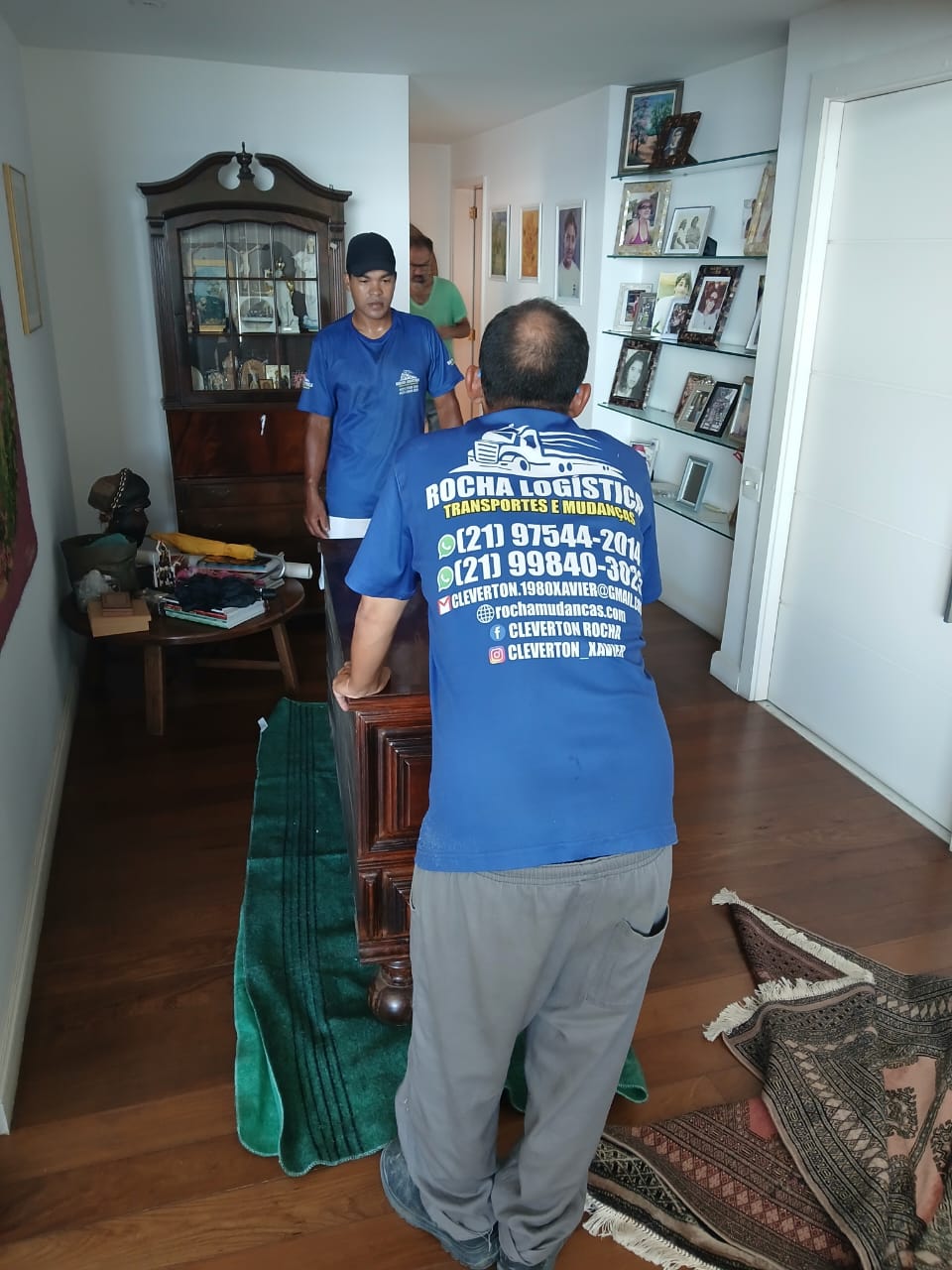 Equipe transportando móveis dentro da residência com uniforme Rocha Logística